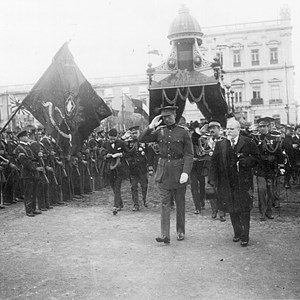 Visita do Rei Alberto I dos Belgas. O Presidente da República António José de Almeida, em primeiro plano, de bengala na mão, acompanhado pelo monarca belga, passam revista à guarda de honra, na praça do Comércio.