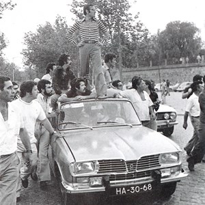 Campanha para as eleições presidenciais de 1976. António Ramalho Eanes, numa atitude de grande coragem, expõe-se de pé num carro descapotável, perante os tiros dos que pretendiam desmobilizar os seus apoiantes.