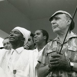 António de Spínola, governador e comandante-chefe das Forças Armadas da Guiné, à direita, durante o discurso de um líder guineense, à esquerda. Spínola promoveu o diálogo sob o lema: «Uma Guiné melhor».