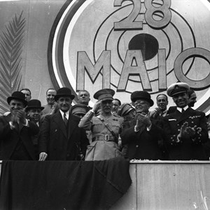 Comemorações do 10.º Aniversário da Revolução Nacional de 28 de Maio de 1926. O Presidente da República Óscar Carmona, em primeiro plano, fazendo continência, acompanhado do presidente do Conselho de Ministros, António de Oliveira Salazar, de outros membros do Governo, e do cardeal patriarca de Lisboa, Manuel Cerejeira, o segundo a contar da esquerda.