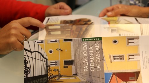 Visitante e funcionária do Palácio da Cidadela trocando impressões sobre o folheto informativo do Palácio da Cidadela.