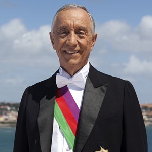 Fotografia oficial do Presidente Marcelo Rebelo de Sousa usando a condecoração esclusiva do Chefe do Estado, a Banda das Três Ordens, símbolo da reunião das Grã-Cruzes das Ordens Militares de Cristo, Avis e Santiago da Espada.