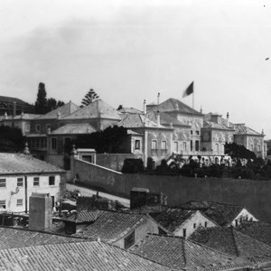 O Palácio de Belém visto do lado poente. No centro da fachada encontra-se hasteado o Pavilhão Real, sinalizando a presença do Rei D. Carlos. É visível a obra de elevação de um piso na ala norte do Palácio, para instalar o ateliê de pintura de D. Carlos.