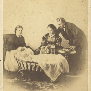 Retrato fotográfico do Rei D. Luís, com a Rainha D. Maria Pia, D. Carlos no berço e a ama de leite, Adelaide Gertrudes de Jesus Dias e Silva. Pormenores curiosos da encenação: na mão direita, a Rainha segura a agulha do seu bordado, no colo; o Rei dirige um olhar meigo sobre o filho, segurando um charuto na mão esquerda, e, no papel de protetor, envolve a Rainha com o braço direito; a ama, vigilante sobre o príncipe que dorme, pousa a mão direita no berço; um livro — talvez uma Bíblia — surge na pequena mesa de apoio. Com esta encenação procurava-se promover um ideal familiar, de que a Família Real seria o primeiro exemplo.