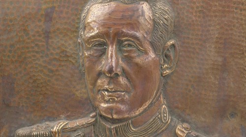 Baixo-relevo em cobre dourado com a representação do busto do Presidente Francisco Craveiro Lopes. Peça com 40 cm de altura por 29,5 cm de largura por 2,5 cm de espessura.