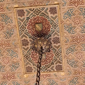 Pormenor do teto da Sala Árabe, onde é possível identificar a representação heráldica da dinastia nacérida, que governou o reino de Granada e construiu o Alhambra. A sua divisa era «Não há vencedor senão Alá».