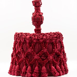 Borla do traje doutoral de Teófilo Braga, 1868. A cor vermelha corresponde à faculdade que concedeu o grau académico. Na parte de cima tem bordadas as iniciais «D.J.T.F.B.» (Dr. Joaquim Teófilo Fernandes Braga).
Doação da família de Flórido Teles de Menezes Vasconcelos.